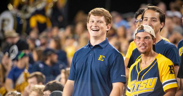 Students in the stands dressed in blue and gold watching a sports event