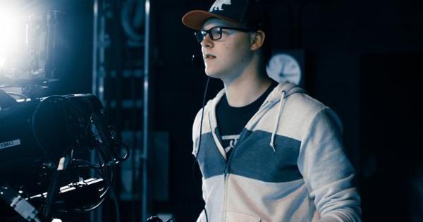 You are looking over the shoulders of two students into a viewscreen of a camera that is recording another student in class.