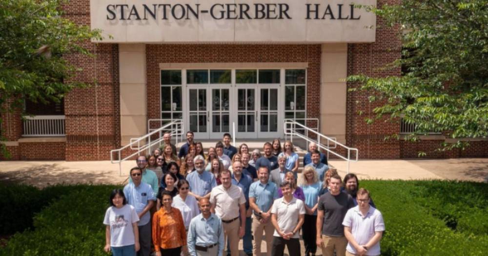 Department of Biomedical Sciences faculty, staff, and students outside of Stanton-Gerber Hall in six rows for a group photo on a sunny day.