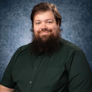 Dr. Alex Hopke, Assistant Professor of Biomedical Sciences pictured wearing a black shirt. of Alex Hopke