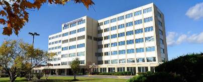 A front view of Indian Path Medical Center. The building is mostly white with glass windows, surrounding greenery.