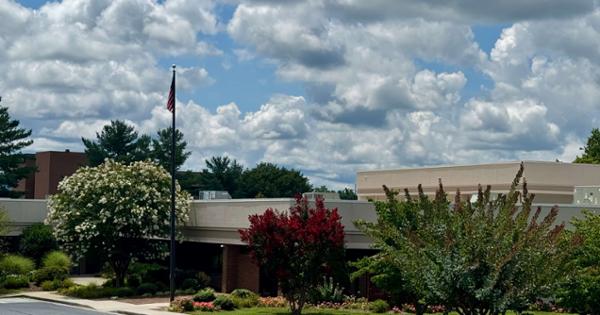 A picture of Woodridge Hospital that shows the American flag and grennery around the building.