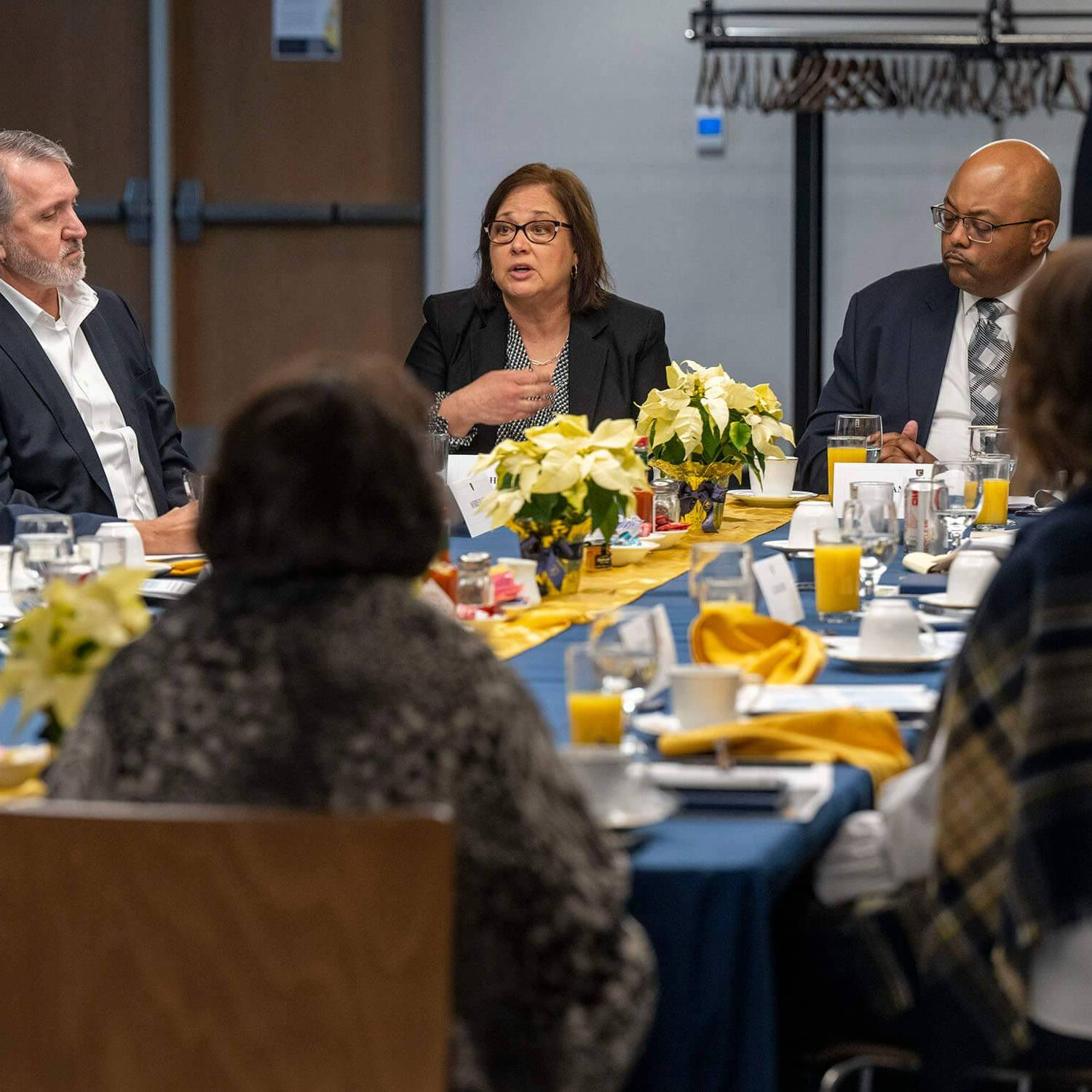 Group of community partners talk around a breakfast table.